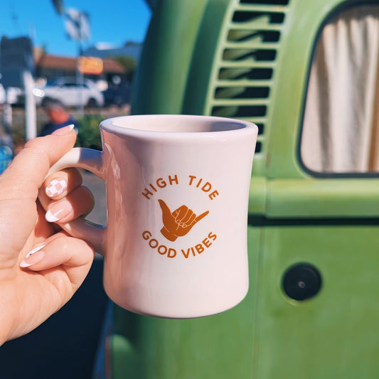 hand holding a coffee mug that says high tide good vibes on it