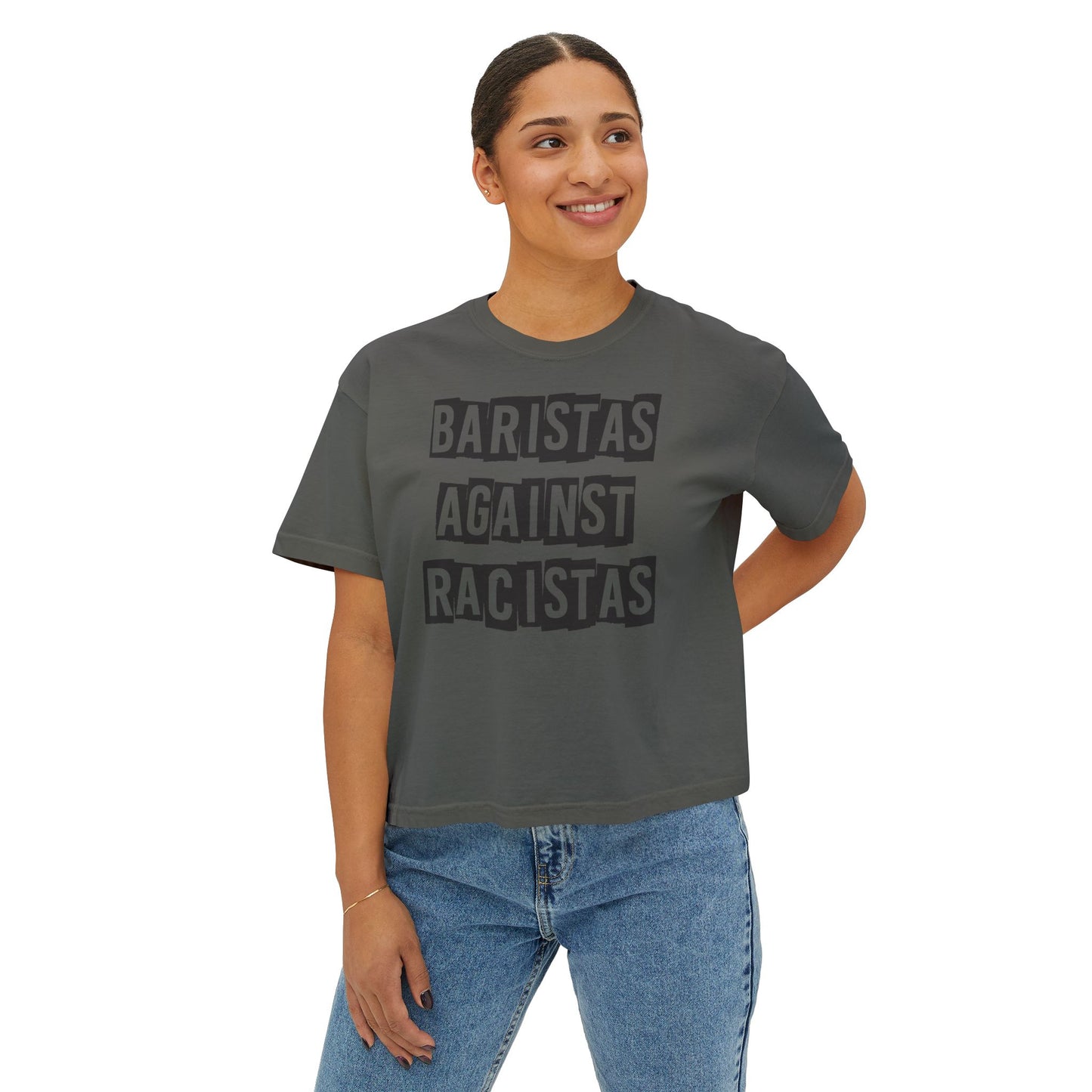 A young lady standing, wearing a dark gray tee shirt that says Baristas Against Racistas