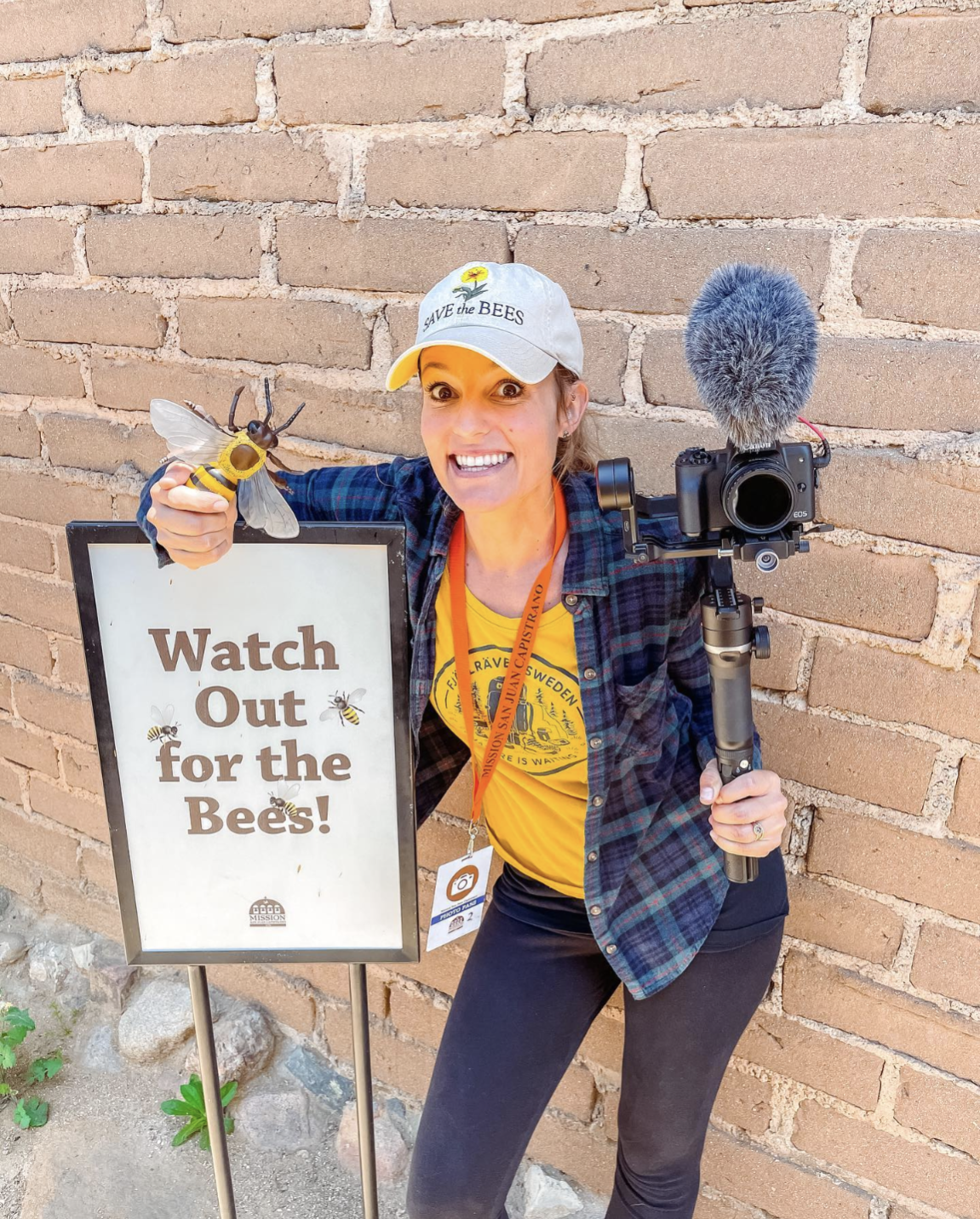 Girl holding a camera next to a sign that says Watch Our for Bees