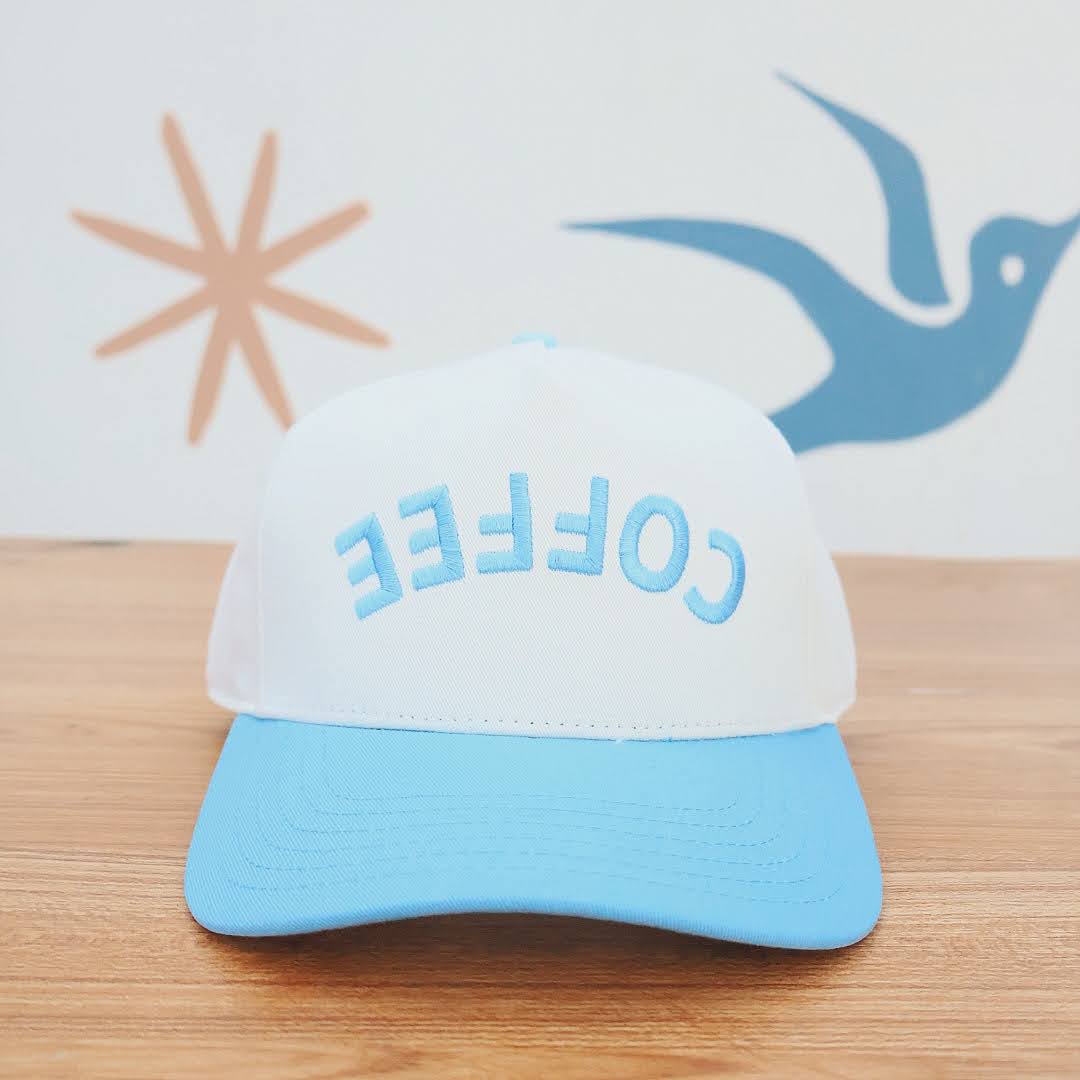 Blue and white cap with 'COFFEE' text on a wooden surface