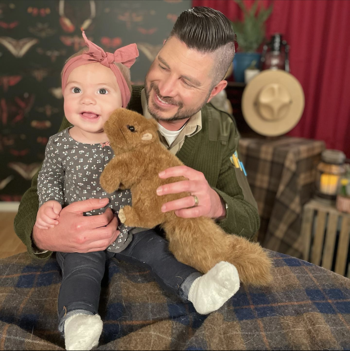 a man holding his daughter and a stuffed squirrel